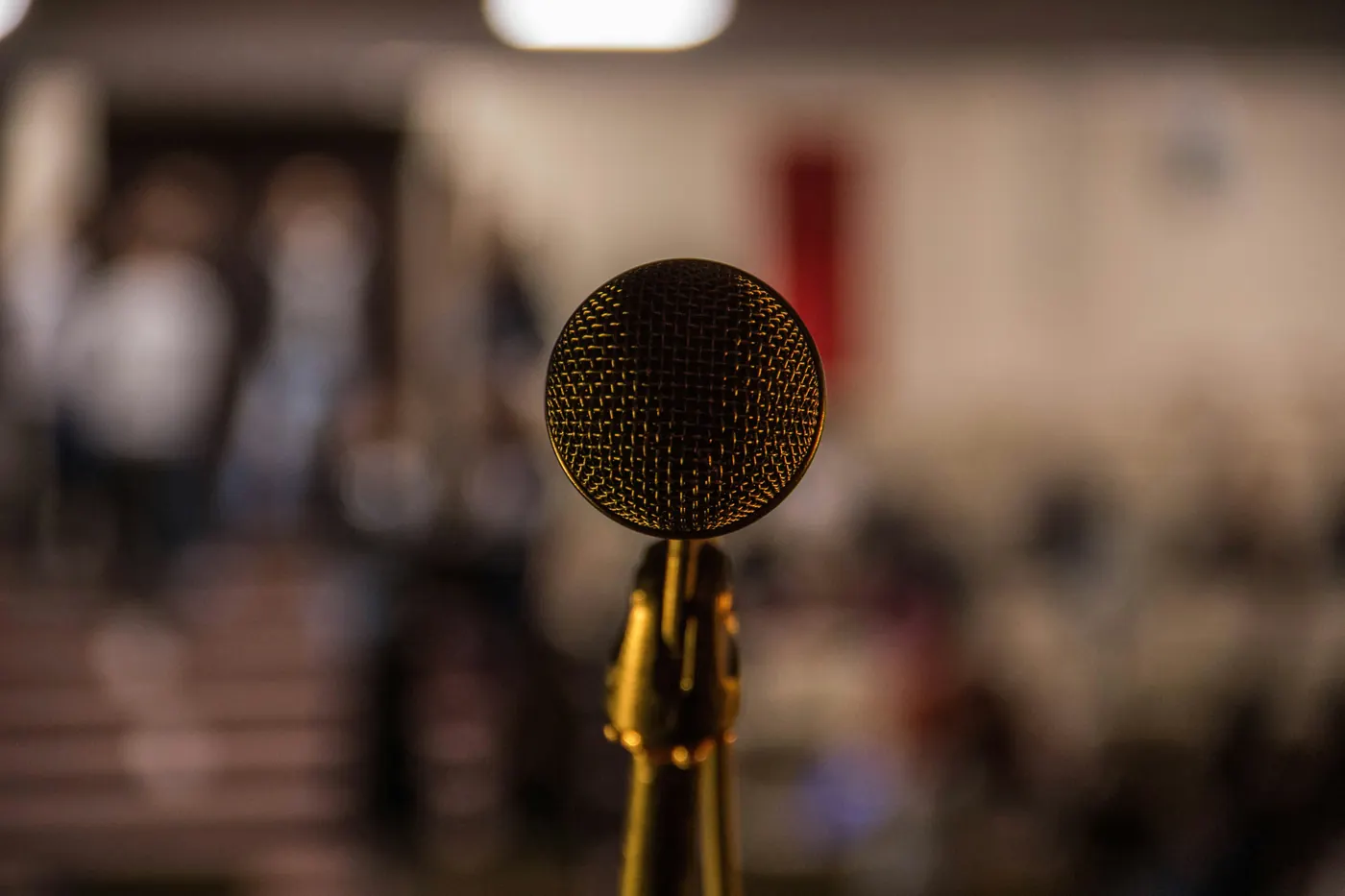 A microphone on a stand in front of a blurred audience